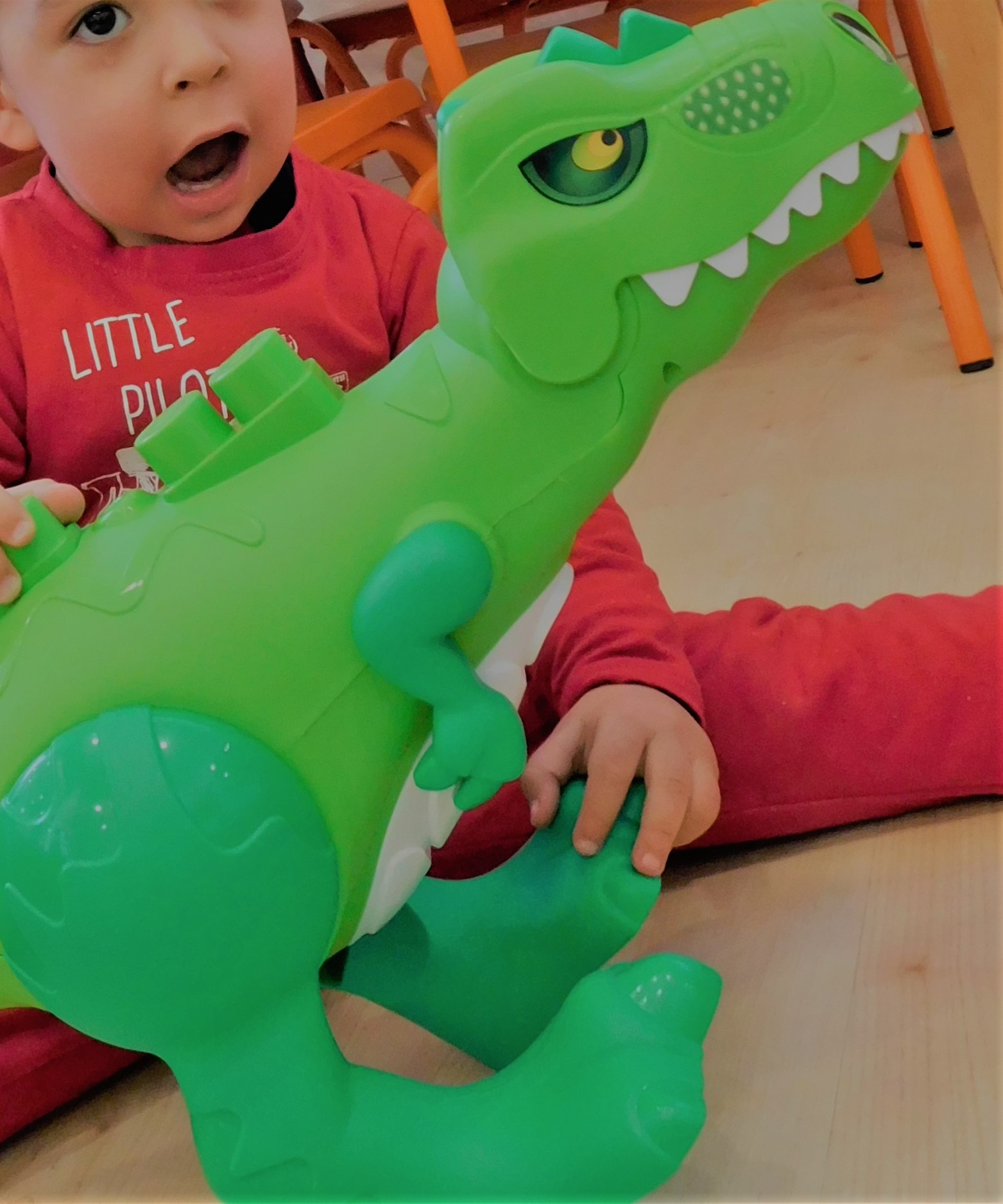 Niño jugando con dinosaurio verde de juguete