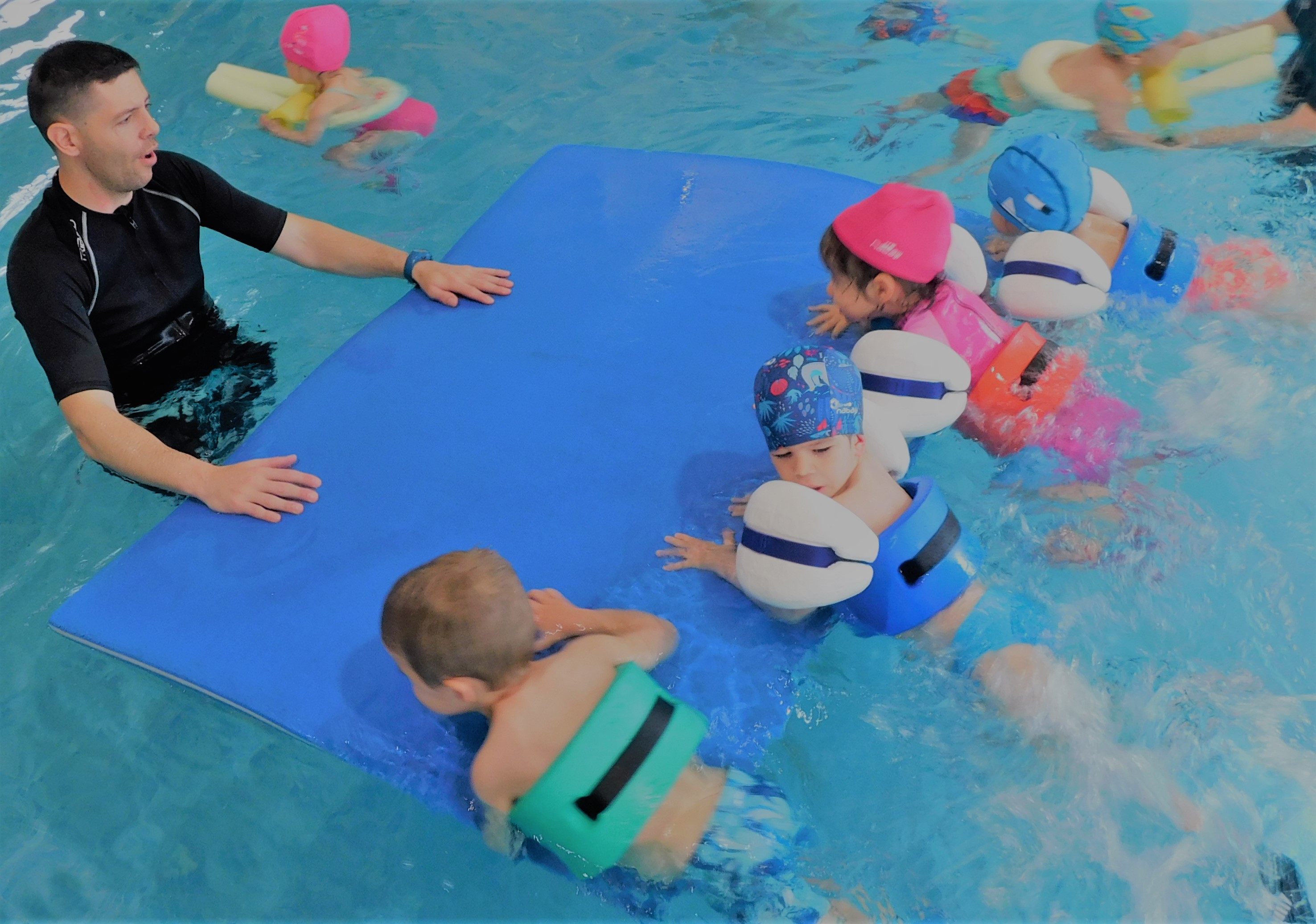 Niños Aprendiendo a Nadar con su maestro presente